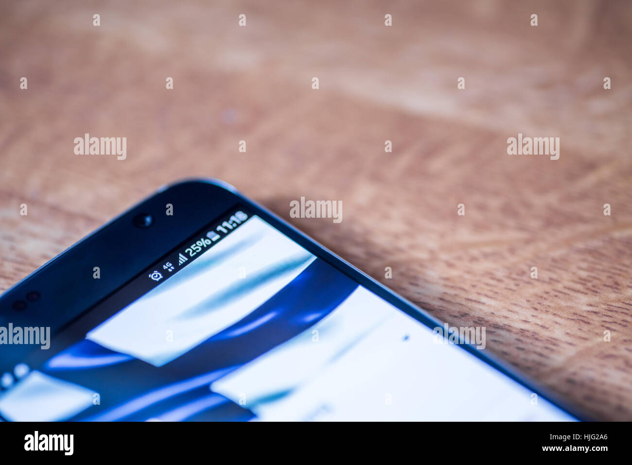 Smartphone sur fond de bois avec 4G Réseau inscription 25  % et la Finlande drapeau sur l'écran. Banque D'Images