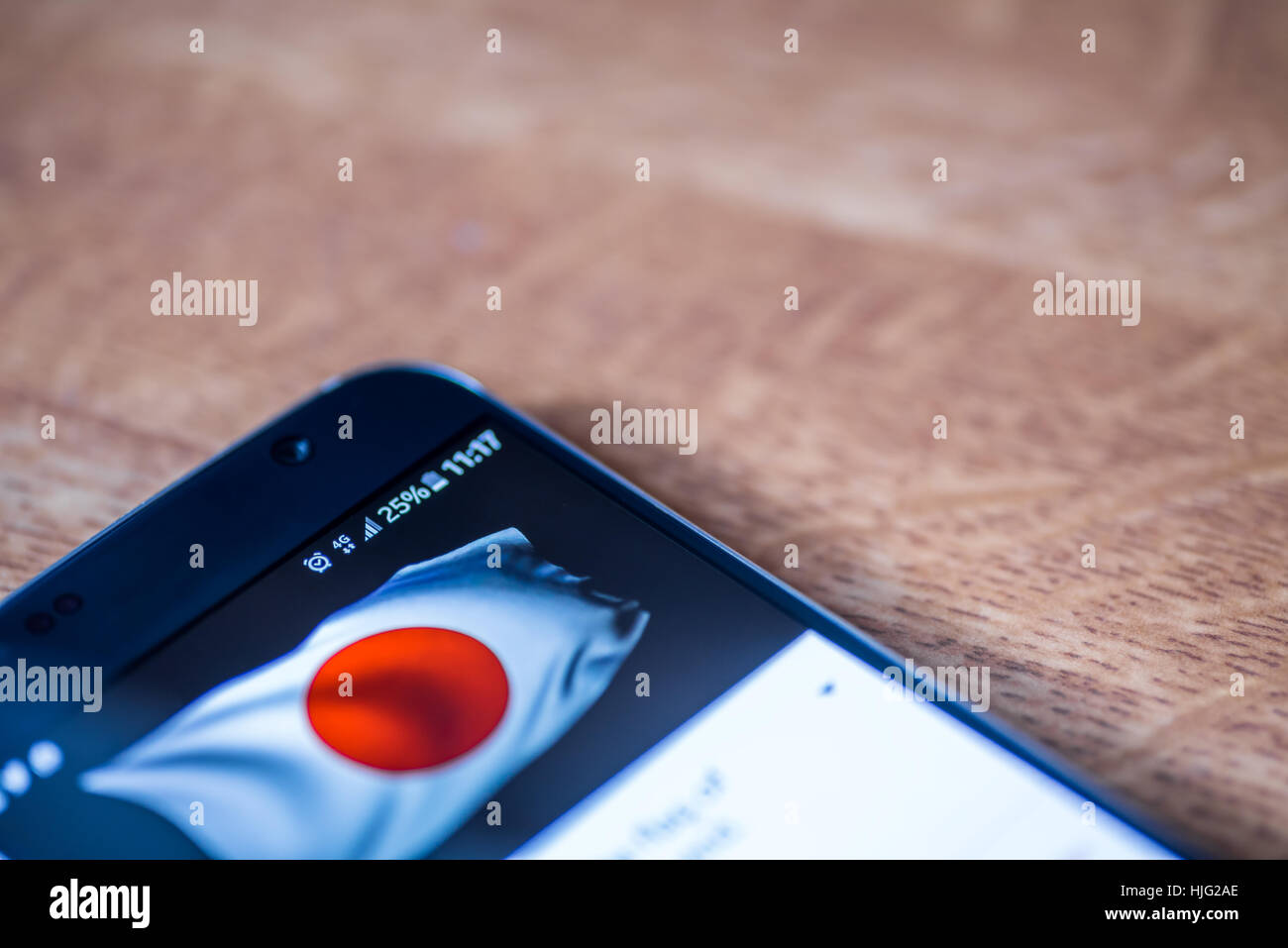 Smartphone sur fond de bois avec 4G Réseau inscription 25  % et le Japon drapeau sur l'écran. Banque D'Images