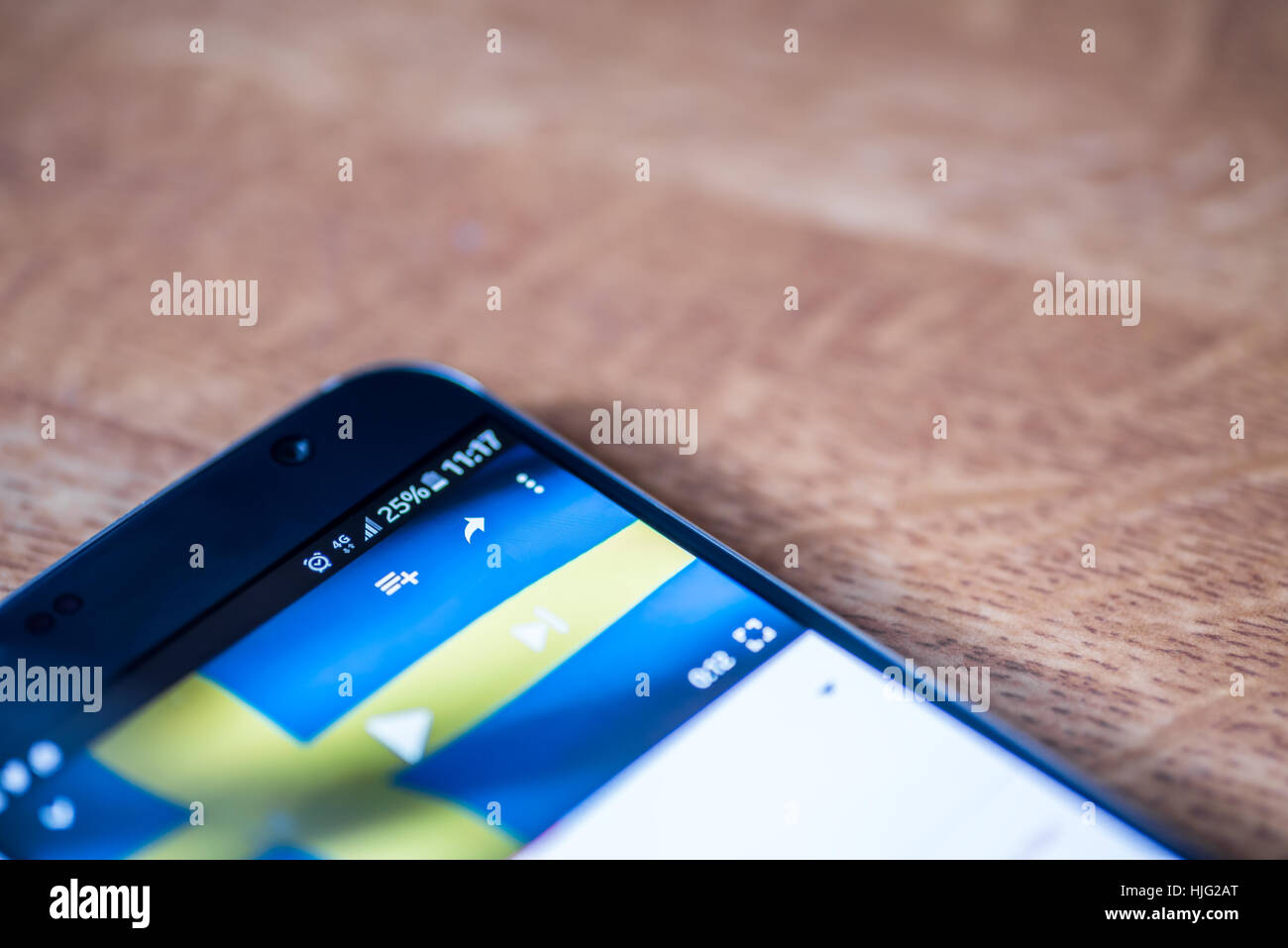 Smartphone sur fond de bois avec 4G Réseau inscription 25  % et la Suède drapeau sur l'écran. Banque D'Images
