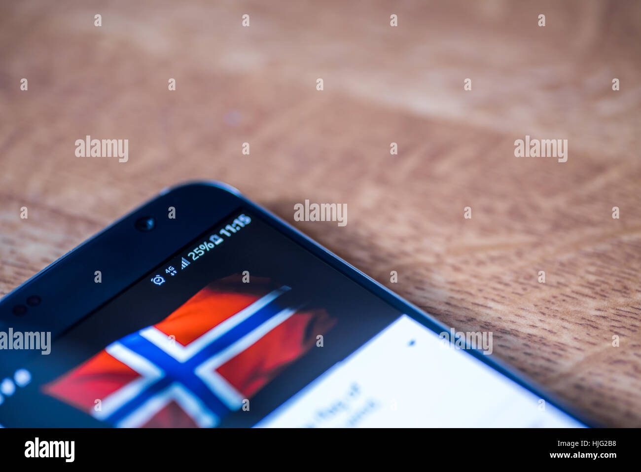 Smartphone sur fond de bois avec 4G Réseau inscription 25  % et la Norvège drapeau sur l'écran. Banque D'Images