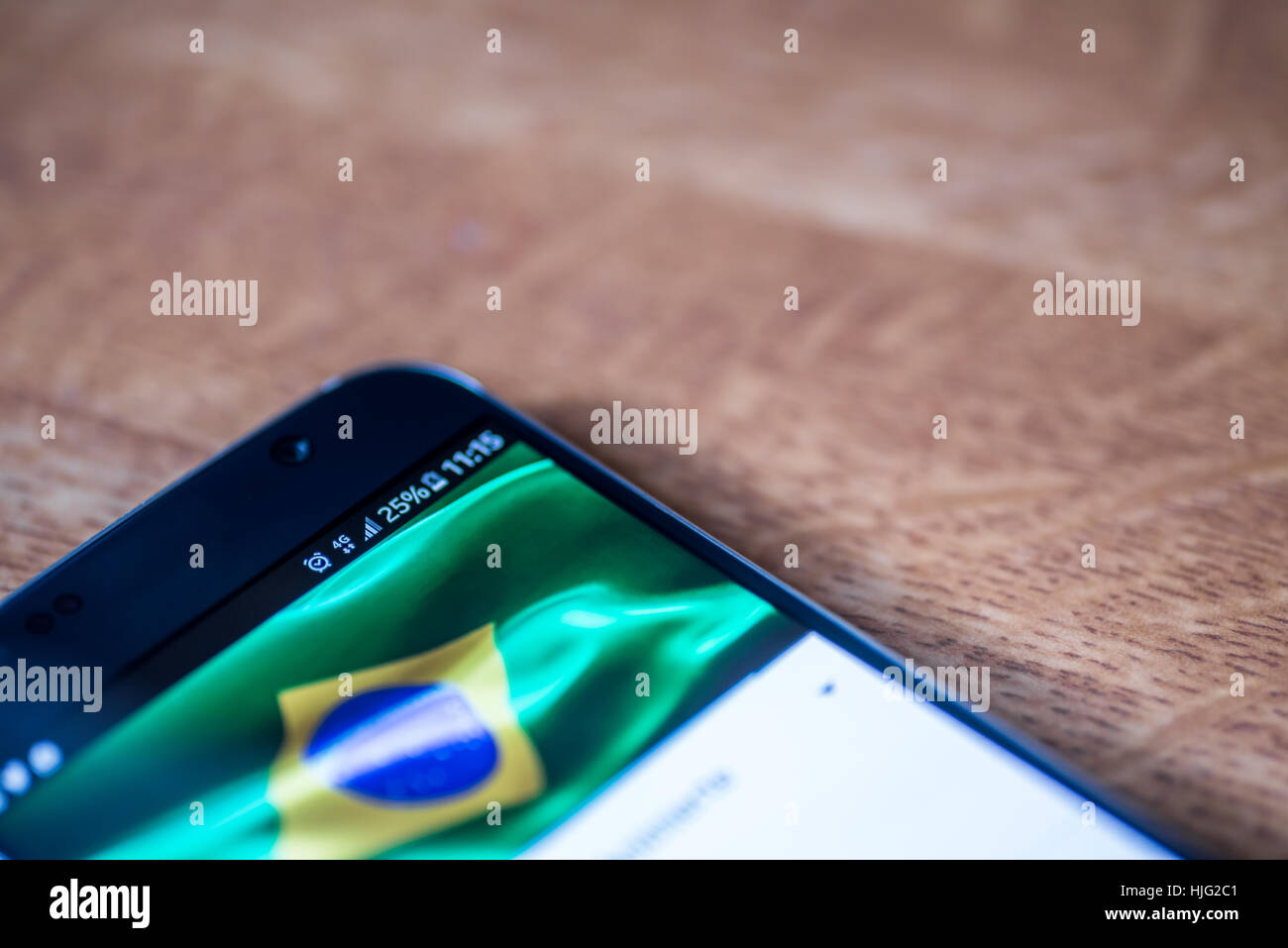 Smartphone sur fond de bois avec 4G Réseau inscription 25  % et le Brésil drapeau sur l'écran. Banque D'Images