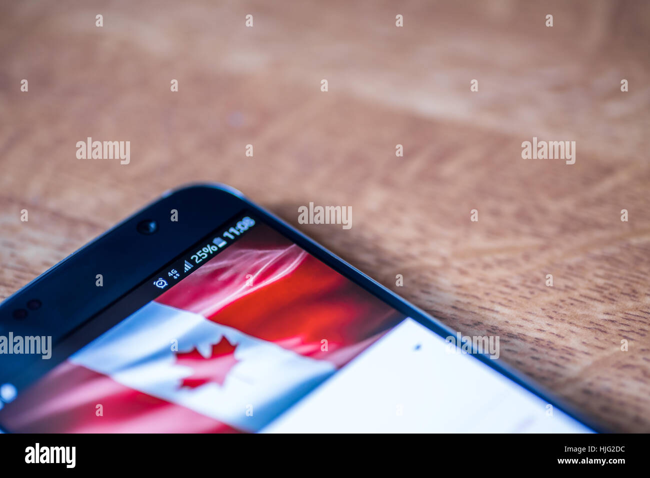 Smartphone sur fond de bois avec 4G Réseau inscription 25  % et le Canada drapeau sur l'écran. Banque D'Images
