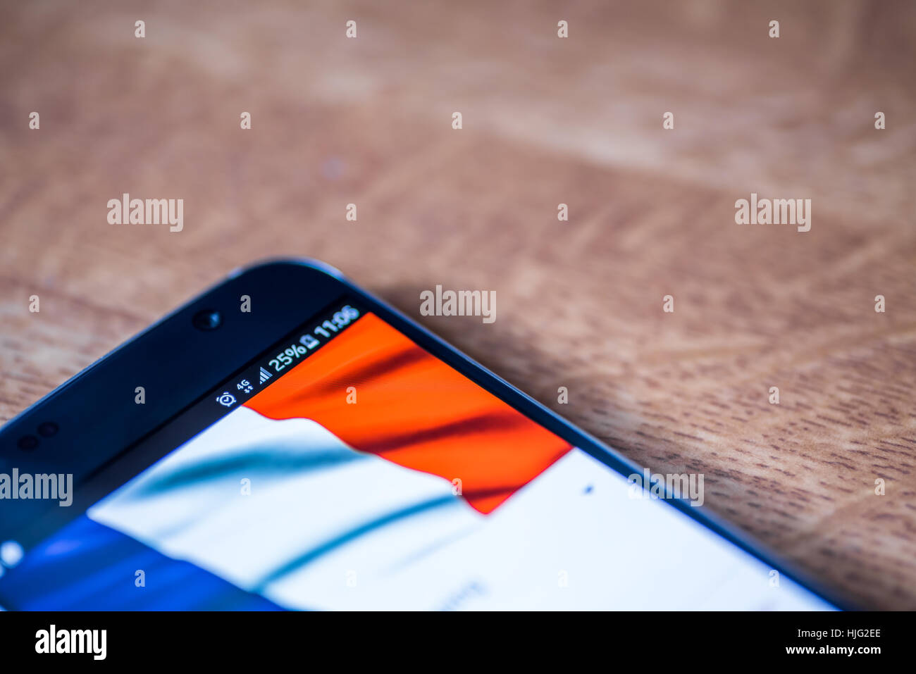 Smartphone sur fond de bois avec 4G Réseau inscription 25  % et drapeau français sur l'écran. Banque D'Images