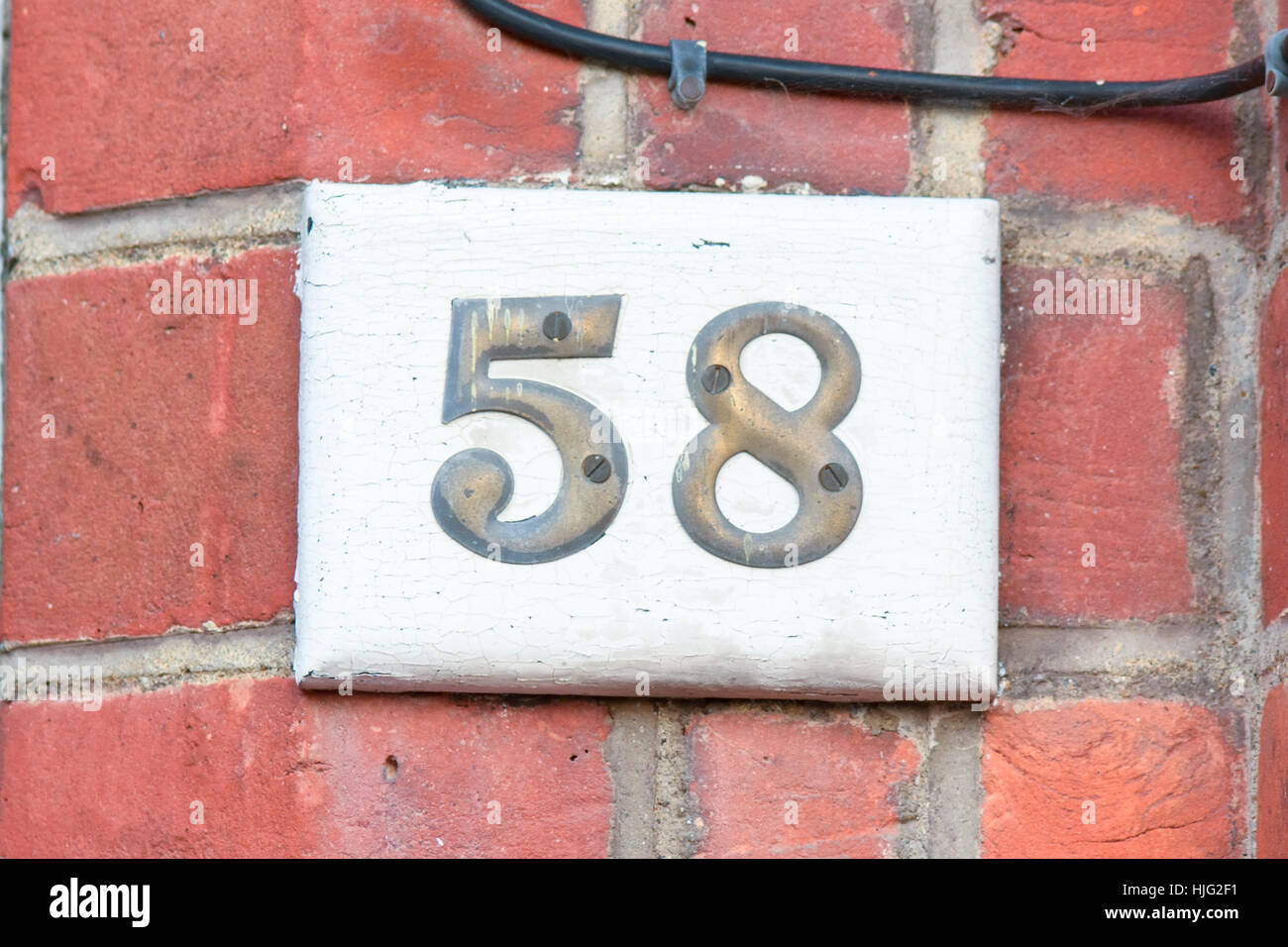 Numéro de maison 58 numéros en laiton - inscription sur un bloc en bois Banque D'Images