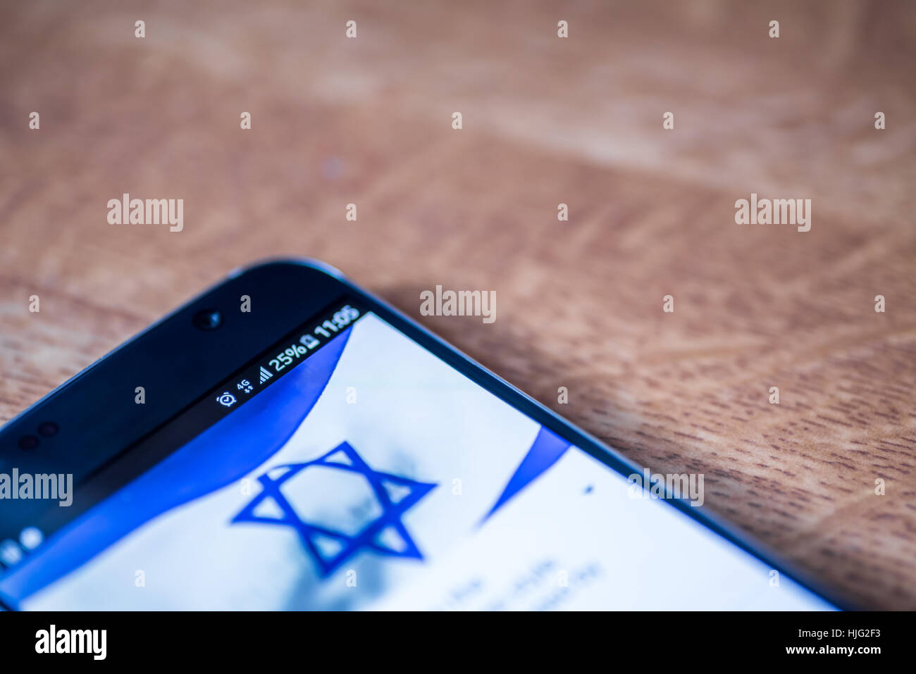 Smartphone sur fond de bois avec 4G Réseau inscription 25  % et Israël drapeau sur l'écran. Banque D'Images