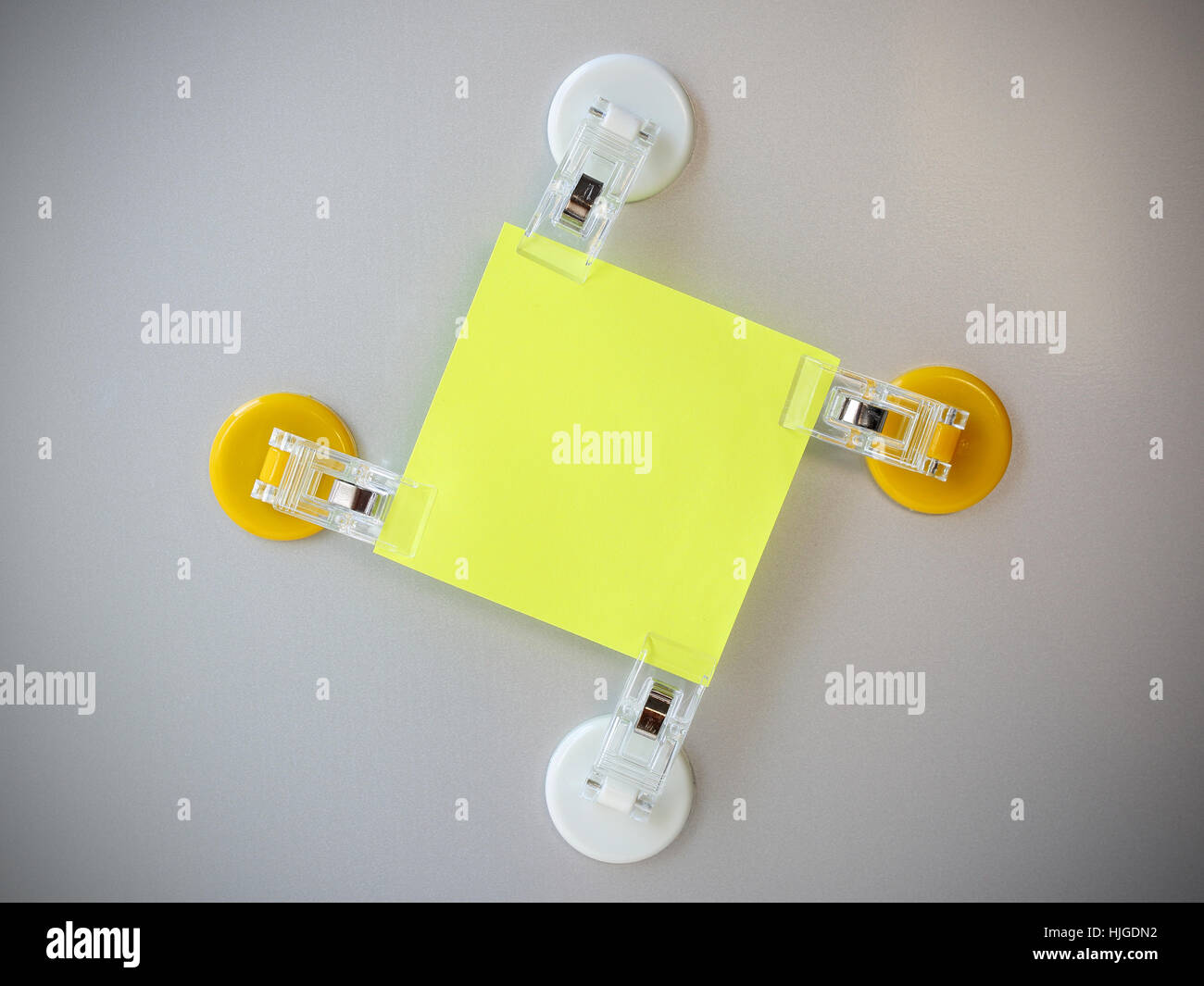 Post it jaune par clip clip blanc et jaune sur fond gris réfrigérateur aimant. Banque D'Images