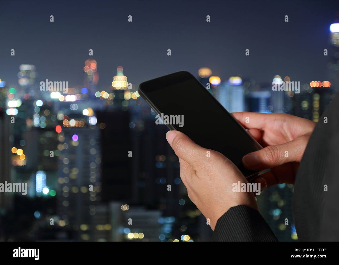 Femme main courante et écran tactile smart phone, portable sur fond de la ville de nuit résumé flou comme concept de l'innovation. Banque D'Images