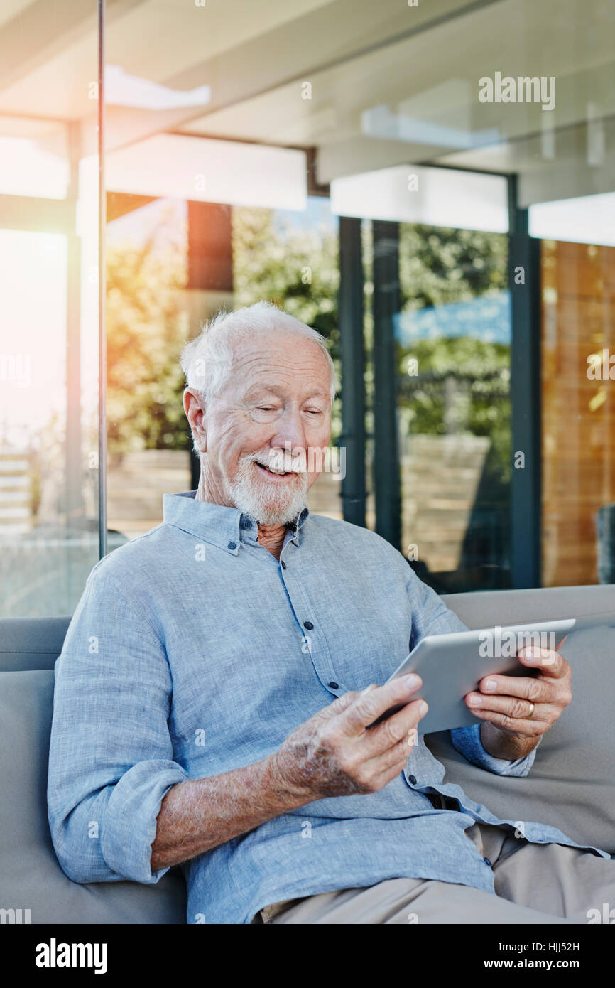 Senior man sitting on terrasse lecture ebook Banque D'Images