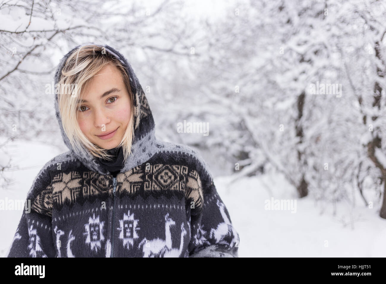 Une jeune femme portant un cardigan debout dans la neige smiling Banque D'Images