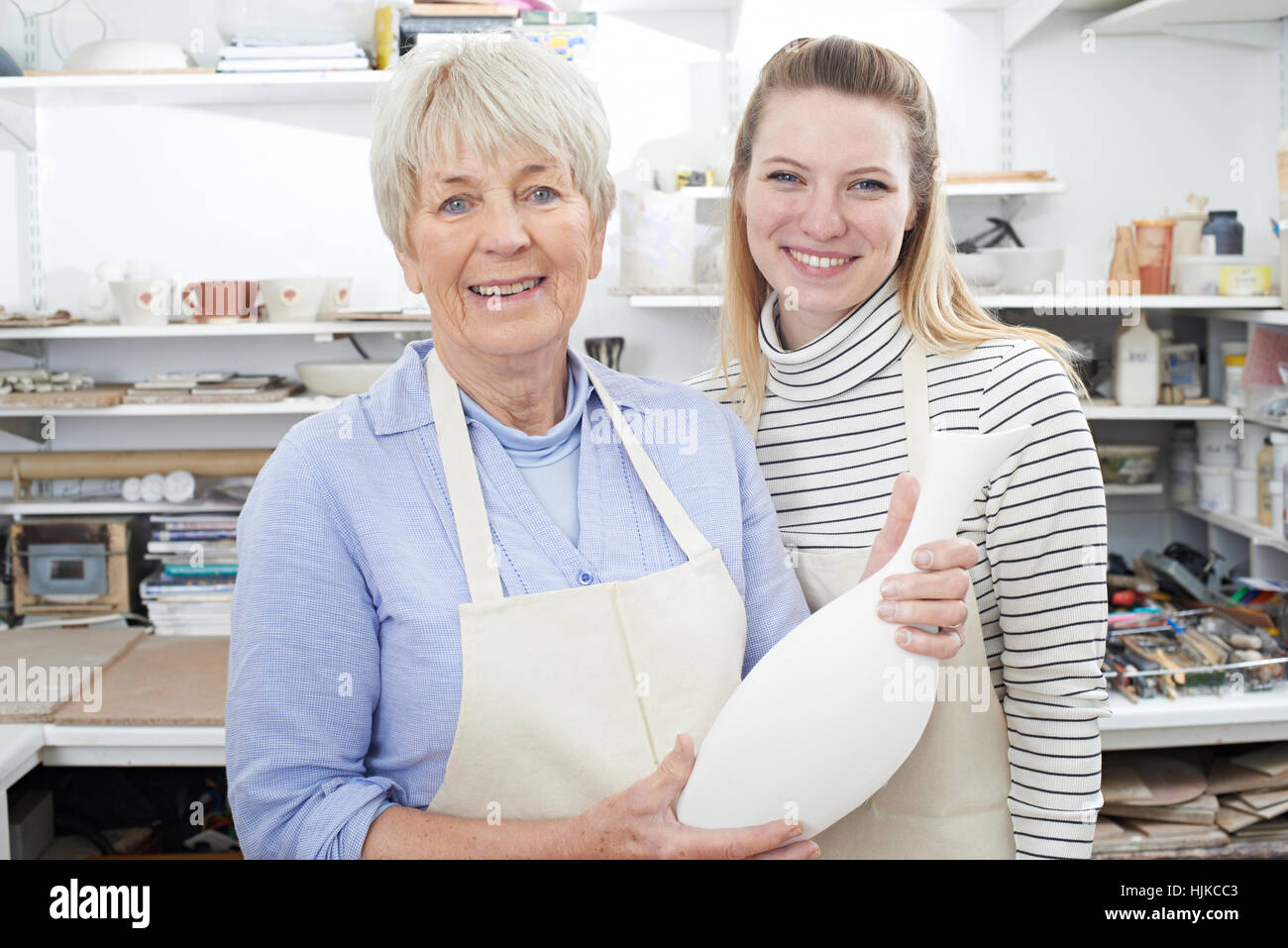 Avec l'enseignant Senior Woman Looking At Vase de classe de poterie Banque D'Images