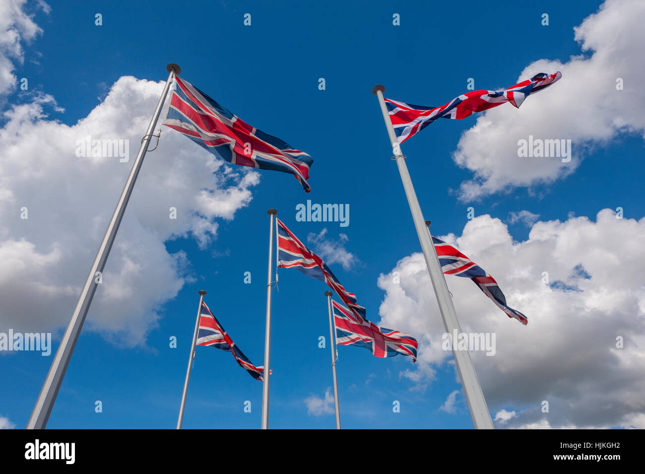 Six drapeaux Union Jack de 6 mâts de drapeau sur un jour ensoleillé, ciel bleu et nuages blancs. Banque D'Images