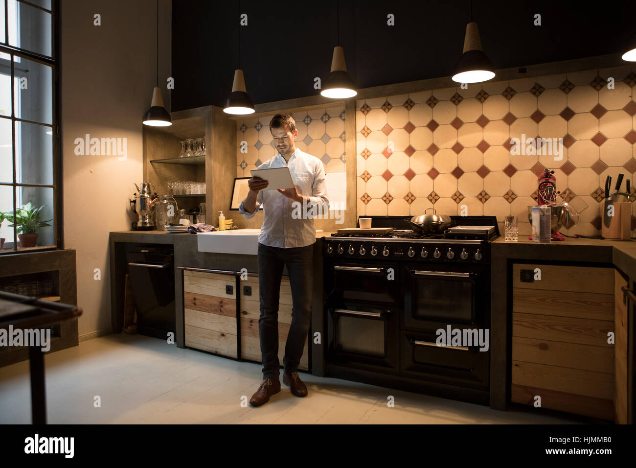 Homme debout dans la cuisine à l'aide de tablet Banque D'Images