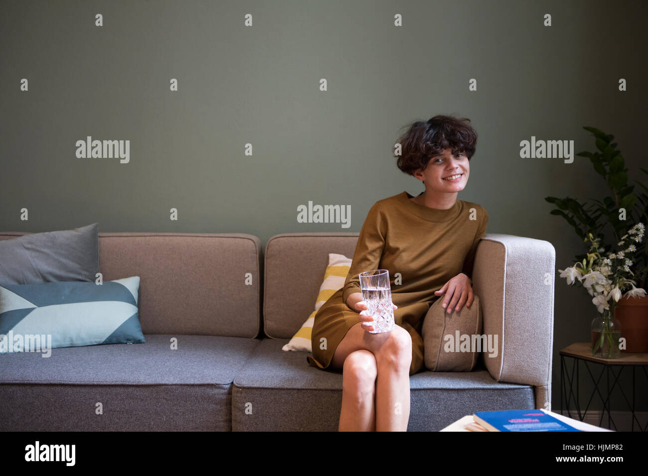 Portrait de jeune femme avec un verre d'eau sur la table à la maison Banque D'Images