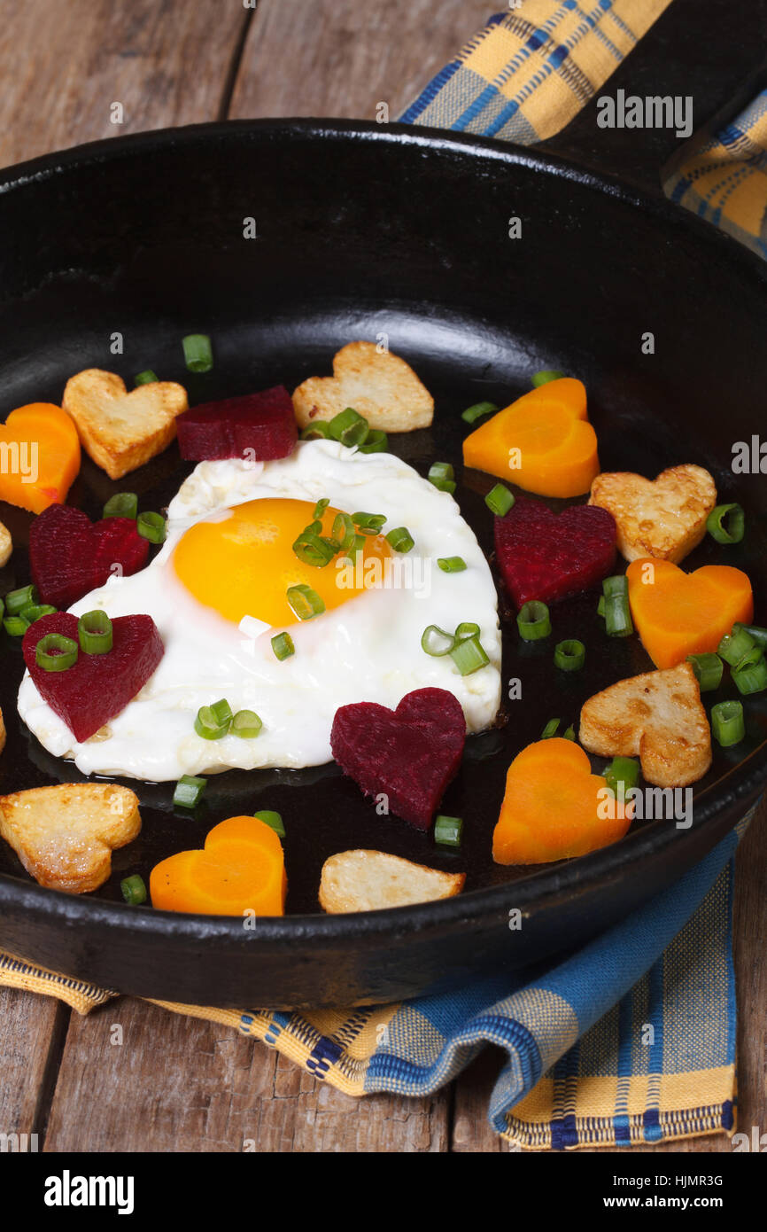 Oeuf dans la forme de cœur dans une casserole avec les légumes libre verticale. Banque D'Images