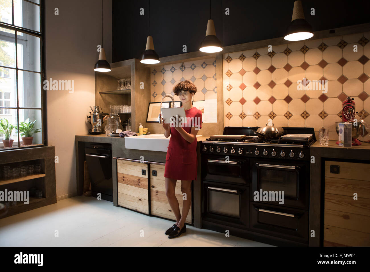 Jeune femme debout dans la cuisine à l'aide de tablet Banque D'Images