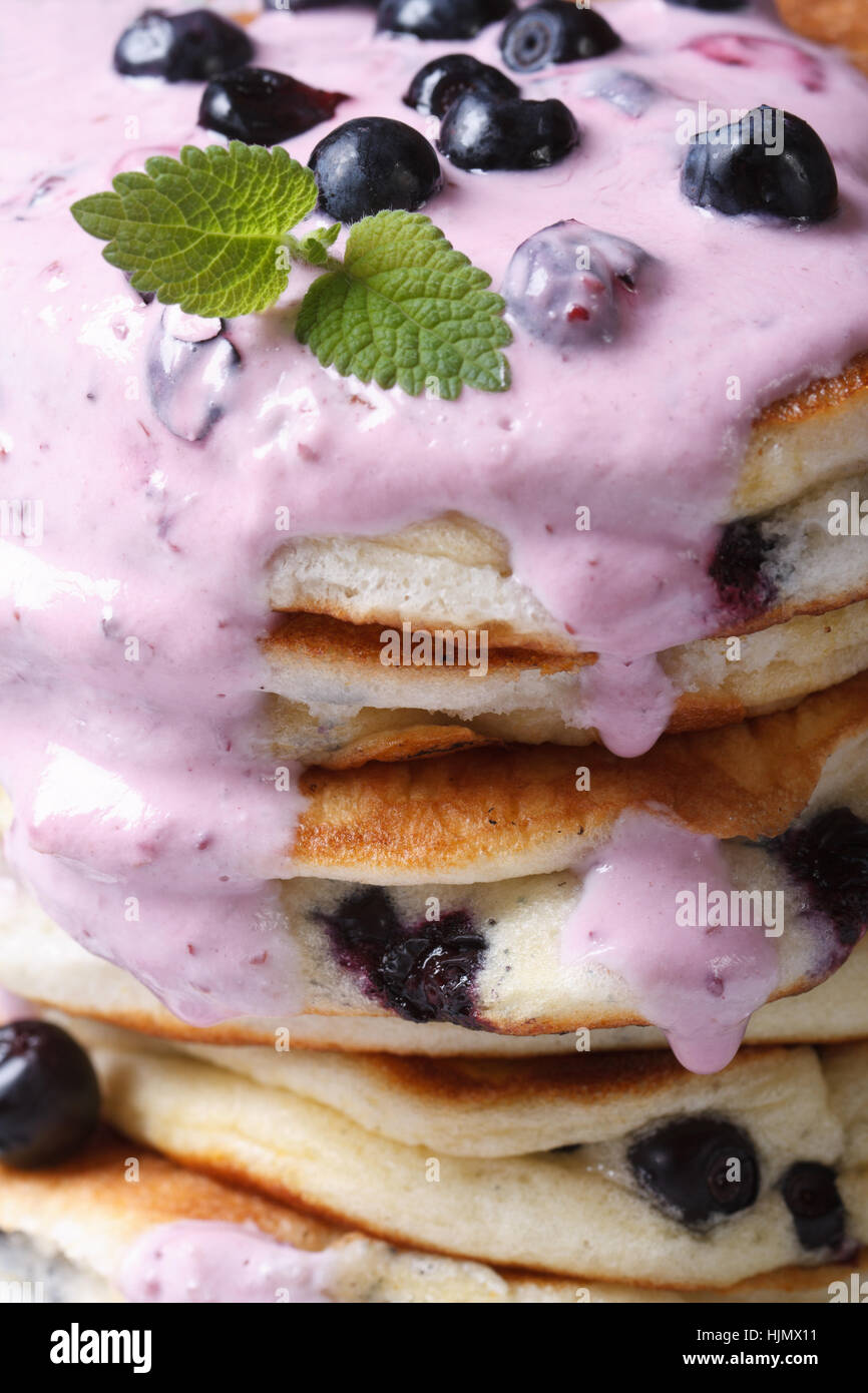 Arrière-plan de l'alimentation. Crêpes aux bleuets avec sauce à la crème et petits fruits macro verticale Banque D'Images