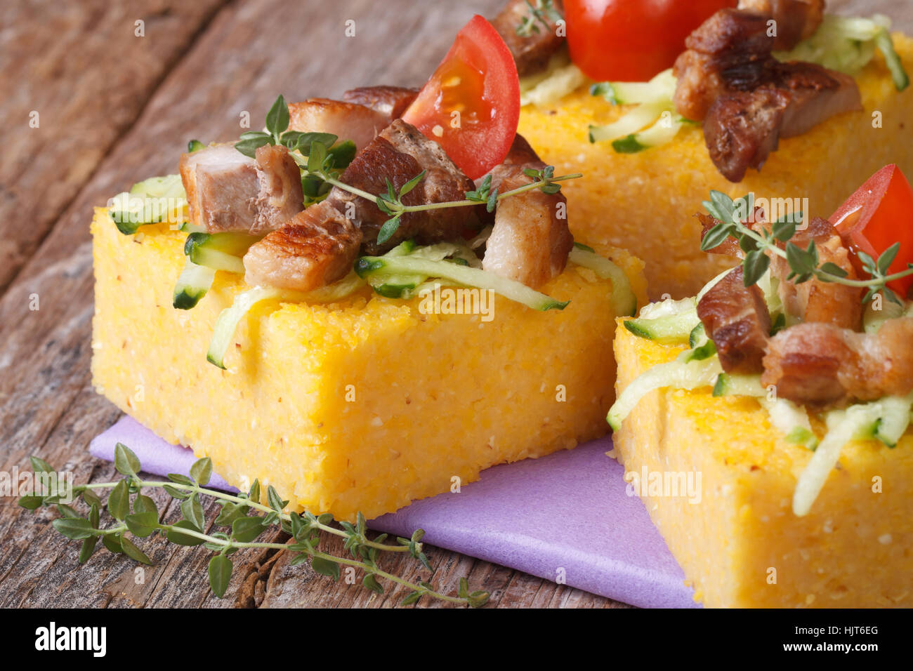 La polenta avec de la viande, la tomate et le thym sur la table horizontale gros plan. Banque D'Images