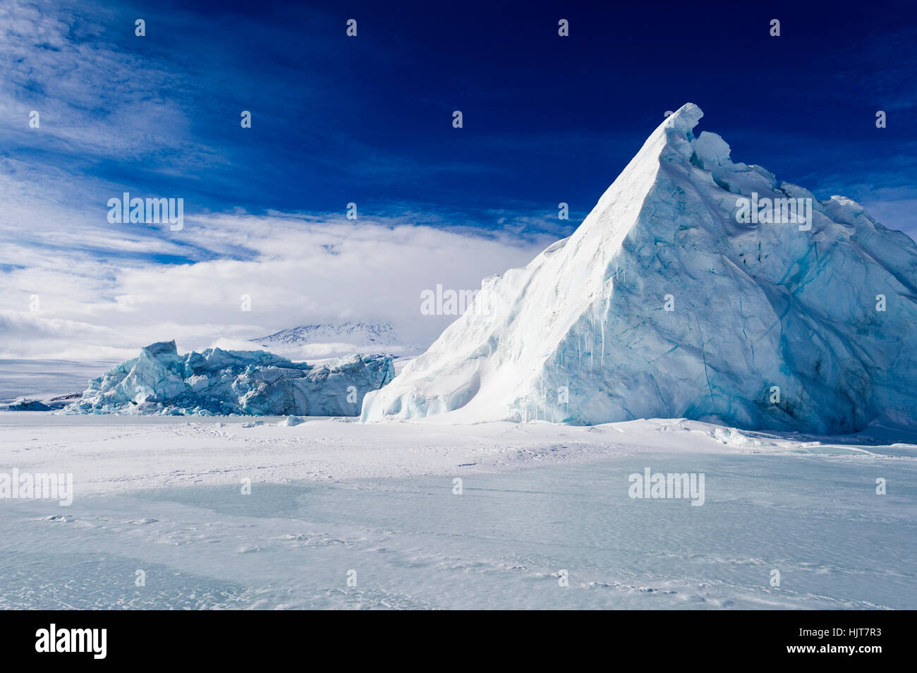 Un énorme iceberg déchiquetée piégés dans la glace de mer congelés. Banque D'Images