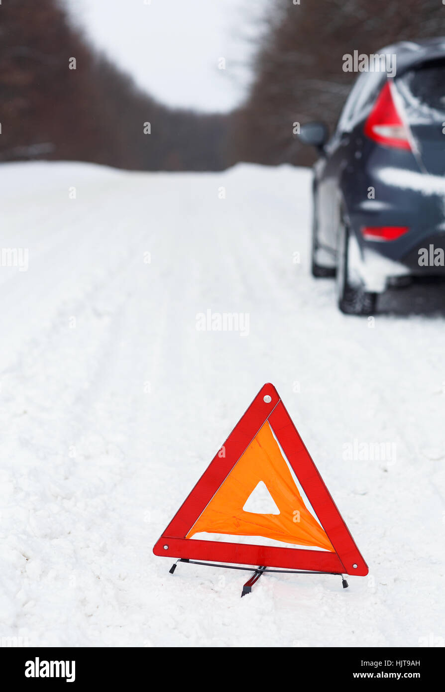 Le transport, l'hiver et véhicule concept - gros plan du triangle d'avertissement rouge avec une voiture en panne Banque D'Images