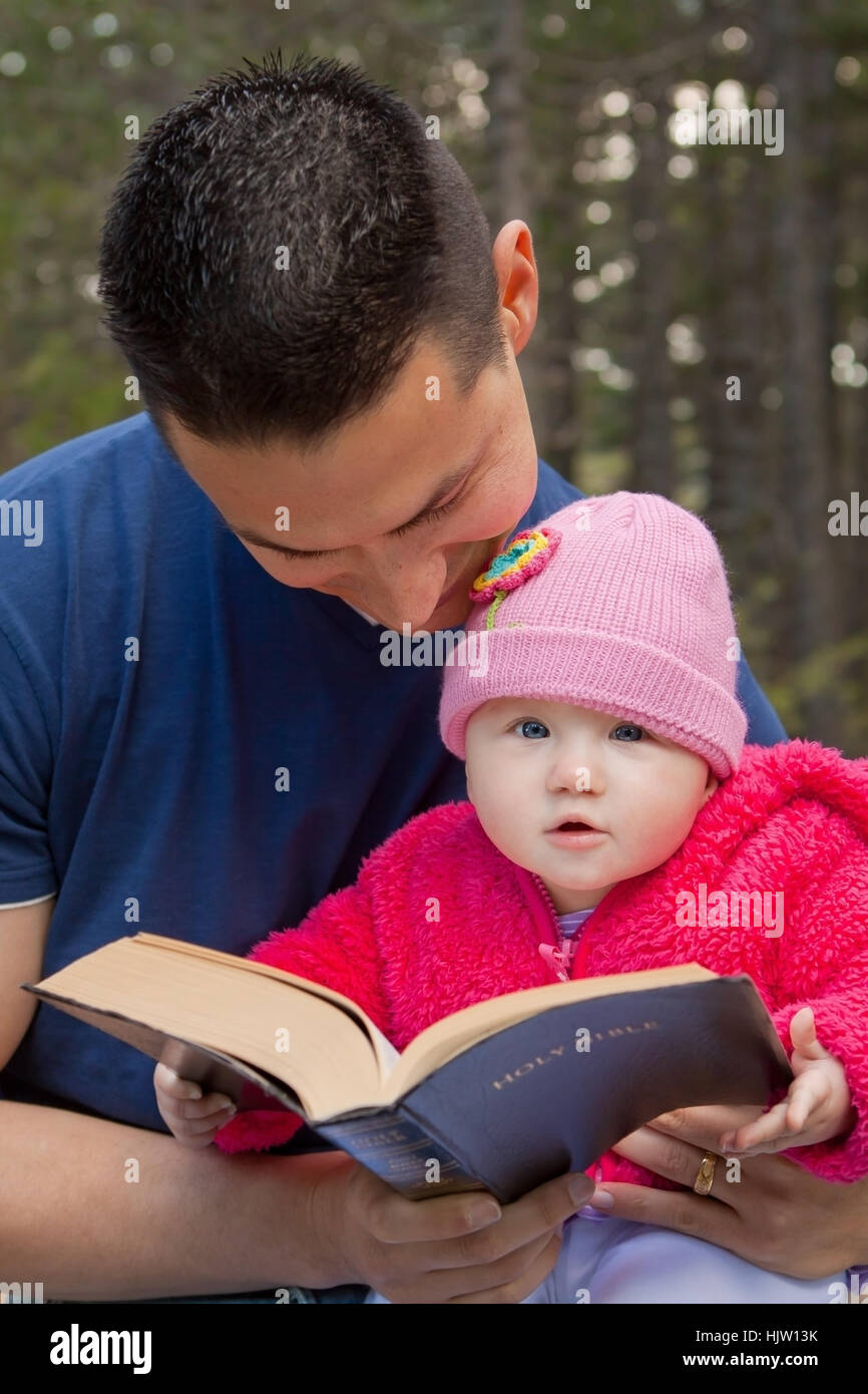 Bébé fille assise sur les genoux de papa la lecture de la Bible KJV (King James Version) Banque D'Images