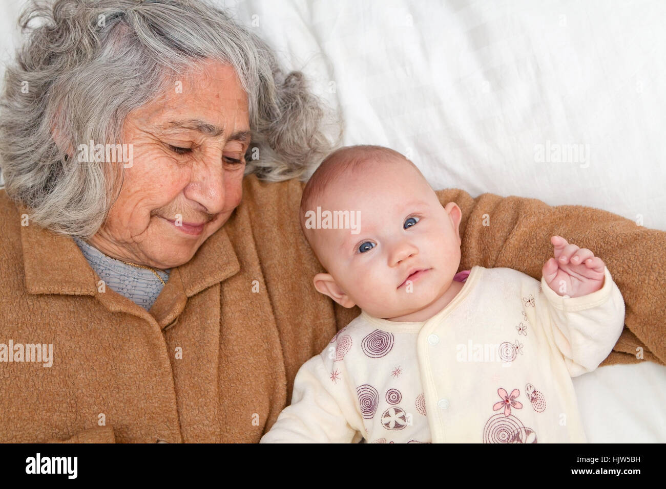 Grand-mère et arrière petite-fille se pelotonnant sur feuille blanche Banque D'Images