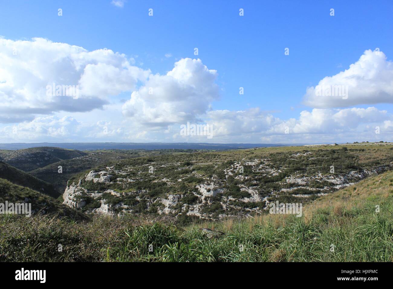 Les Cumulonimbus flottent dans un ciel bleu sur les collines de la Sicile. Banque D'Images