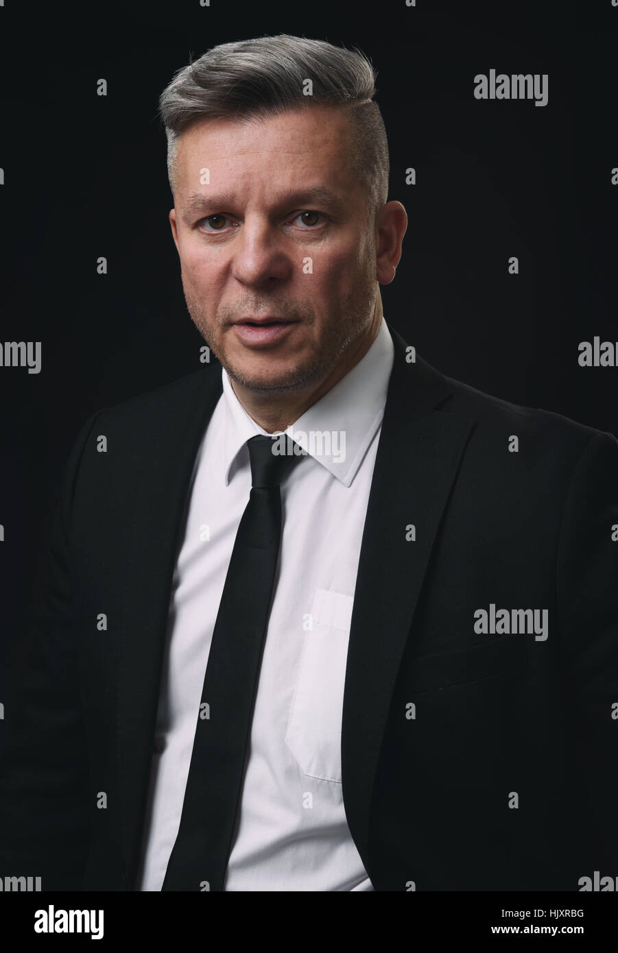 Senior businessman sérieux en costume noir et chemise blanche. Banque D'Images