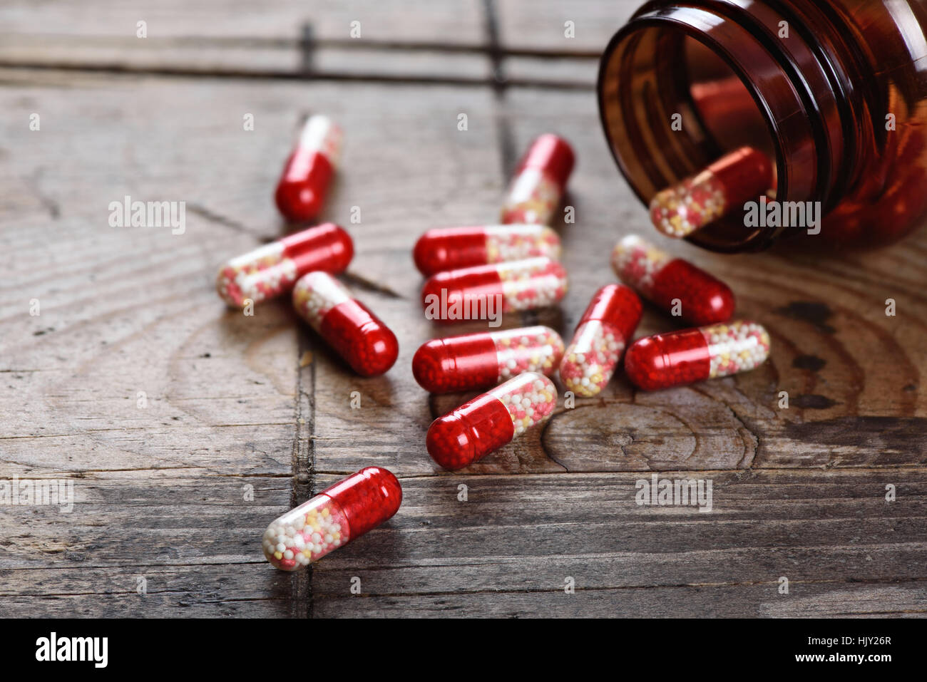 Bouteille de pilules pilules déversant sur table en bois. Capsules médecine Banque D'Images