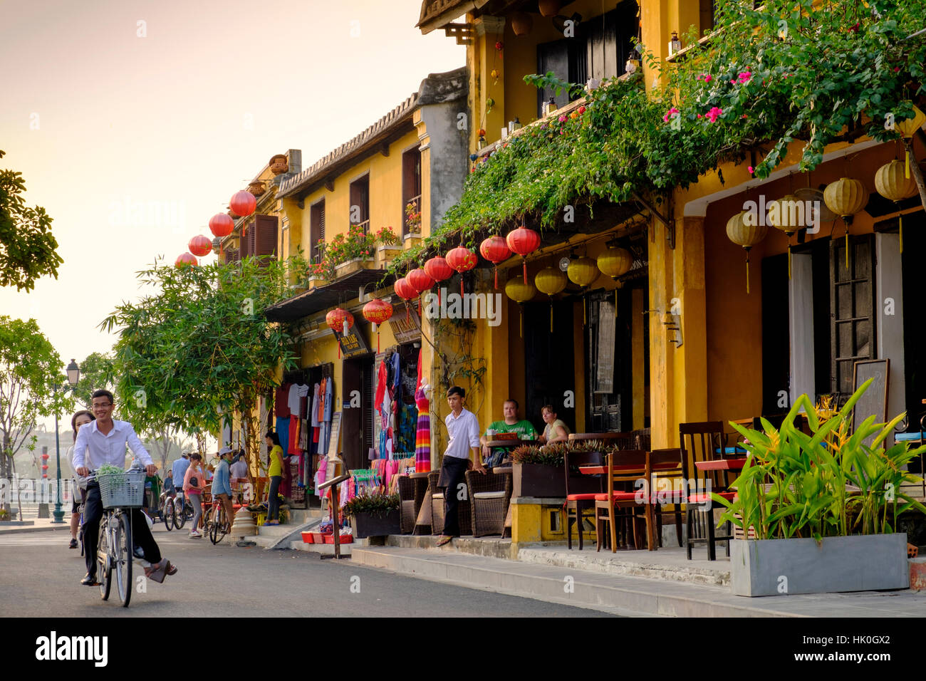 Jeune couple riding a bicycle passé attrayant café shop maisons dans Hoi An, Vietnam, Indochine, Asie du sud-est Banque D'Images