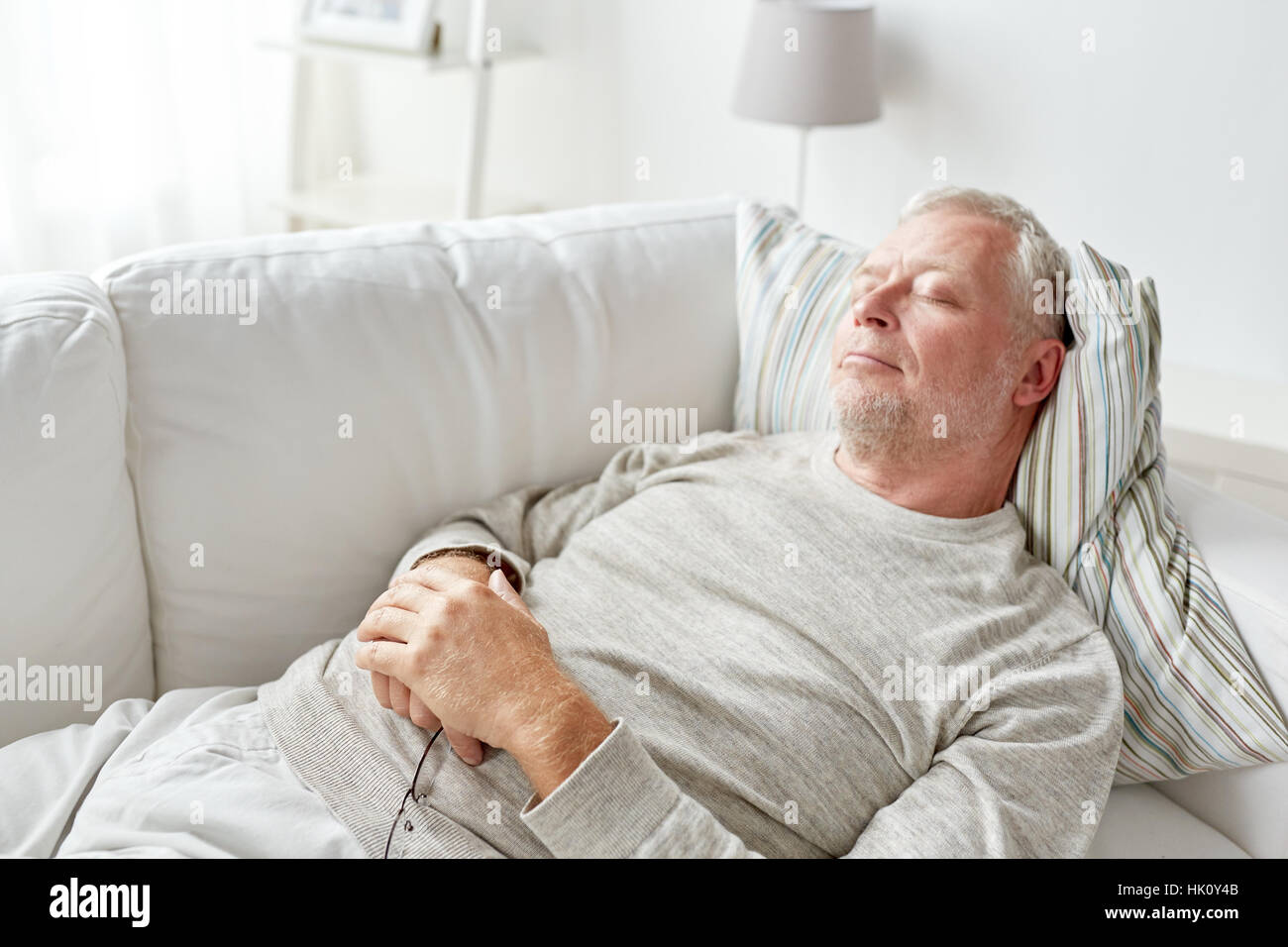 Senior man sleeping on sofa at home Banque D'Images