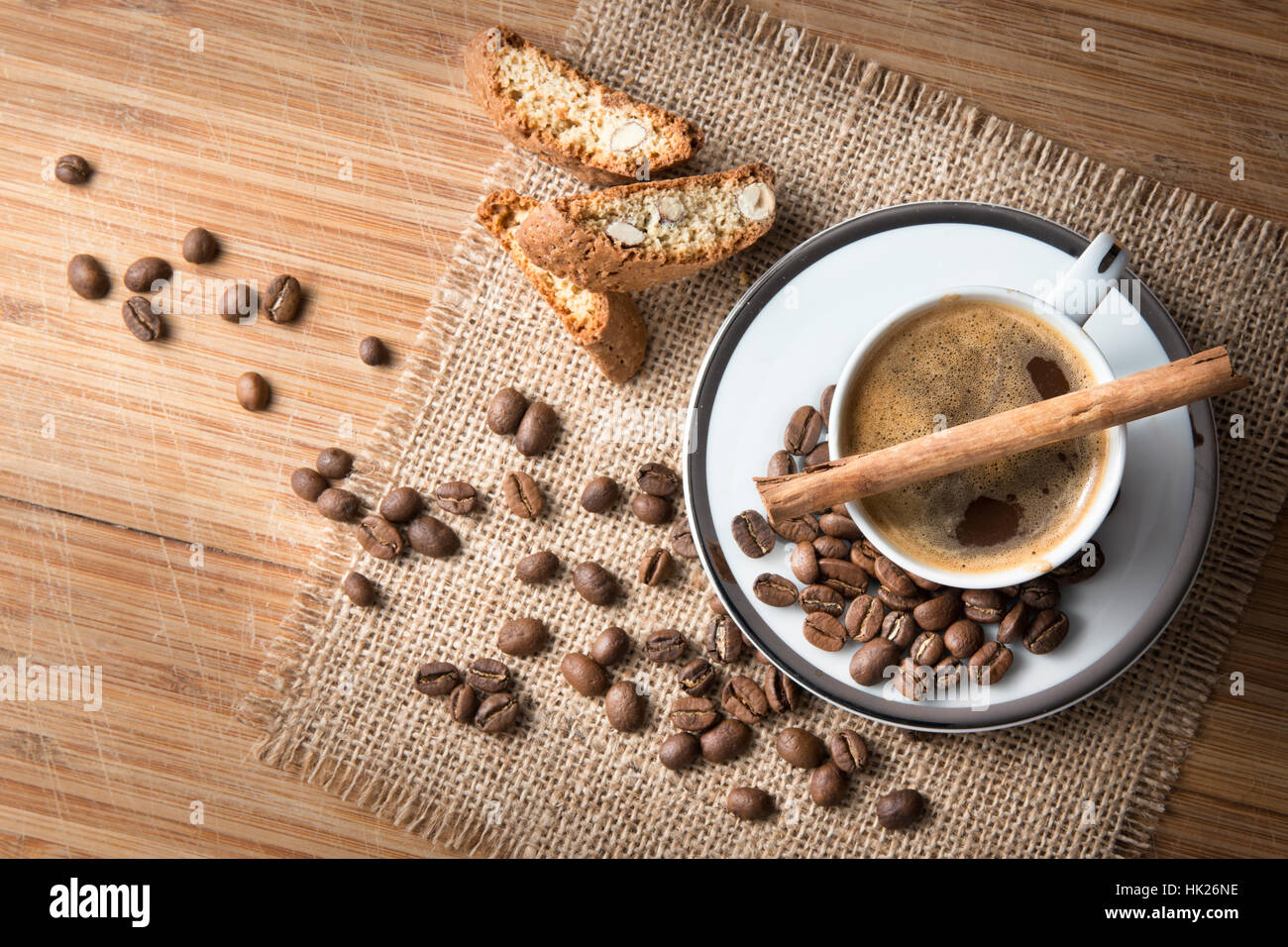 Un studio, nature morte d'une tasse de café sur une soucoupe avec un bâton de cannelle, fèves grillées et des biscuits sur un tapis de jute Banque D'Images