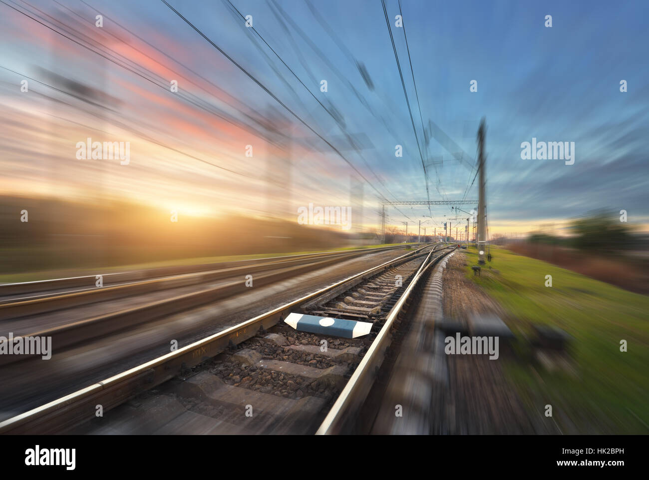 Railroad in motion au coucher du soleil. Gare avec effet de flou coloré contre ciel ensoleillé, concept industriel Contexte Banque D'Images