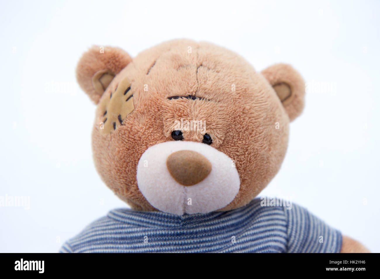 Un mignon petit ours en peluche brun dans la neige avec T-shirt rayé bleu et les mots 'me pour vous' sur sa patte arrière Banque D'Images