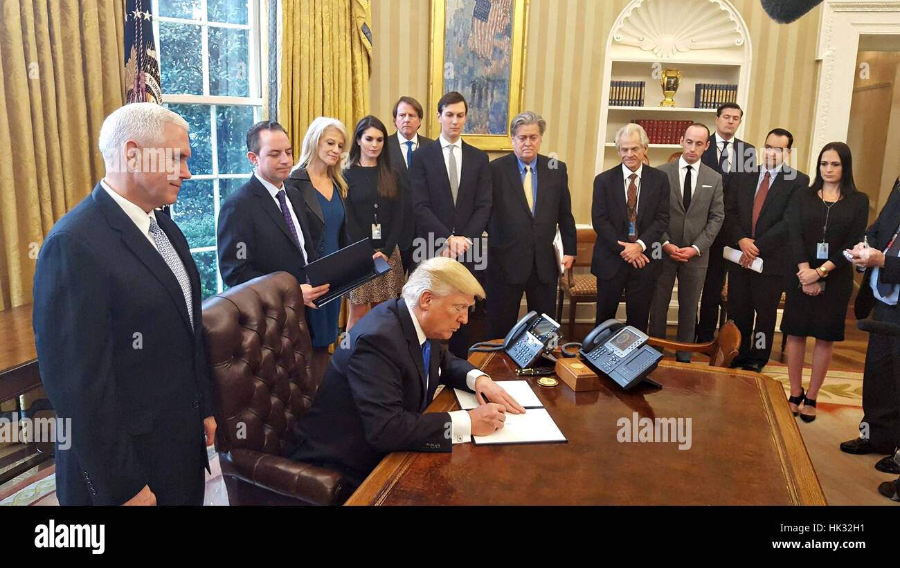 Président américain Donald Trump signe un ordre exécutif pour faire avancer la construction du pipe-line Accès Dakota entouré par le personnel dans le bureau ovale de la Maison Blanche le 24 janvier 2017 à Washington, D.C. à la recherche sur de gauche à droite sont : Vice-président Mike Pence, Chef de Cabinet de la Maison Blanche Reince Priebus, conseiller du président Kellyanne Conway, Directeur de la communication de la Maison Blanche espère que Hicks, Senior Advisor Jared Kushner, et Conseiller principal Stephen Bannon. Banque D'Images