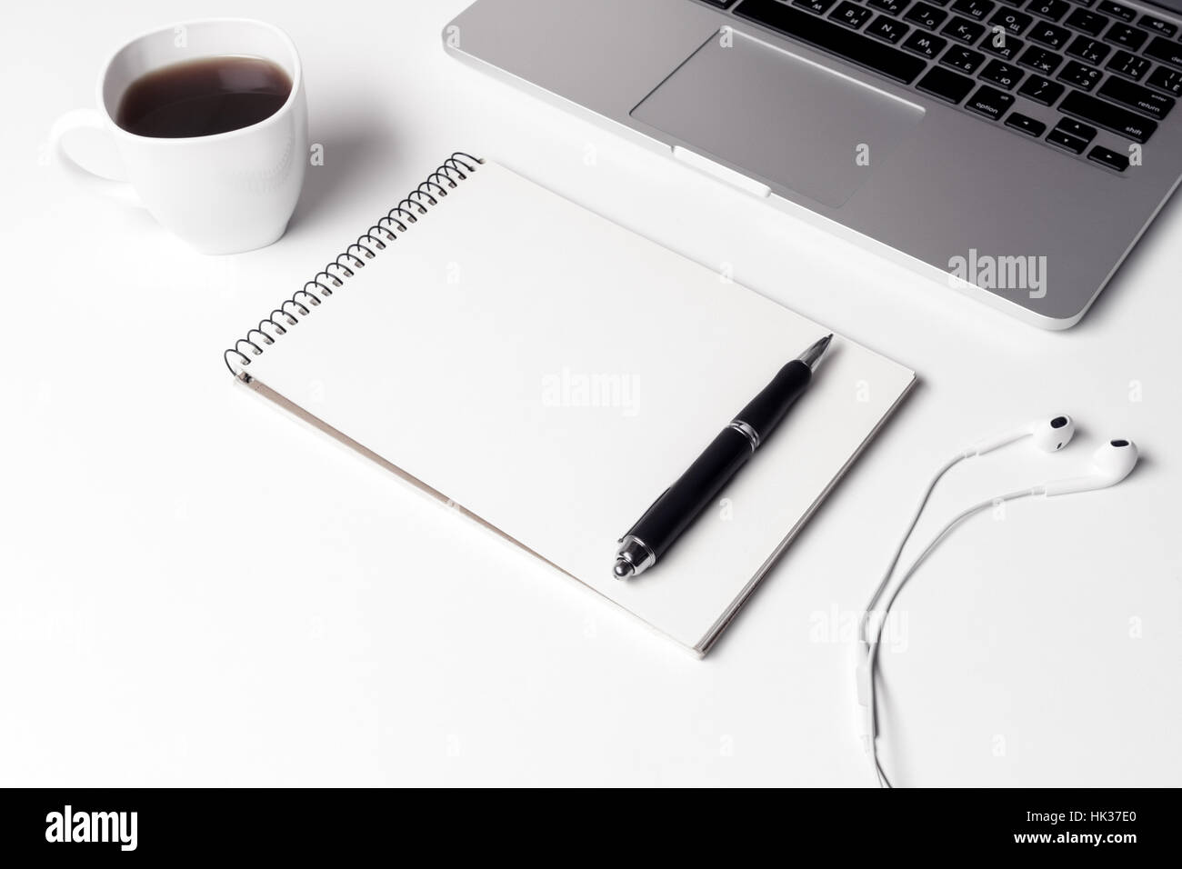 Tasse à café, ordinateur portable avec écouteurs et stylo près de coffre Banque D'Images