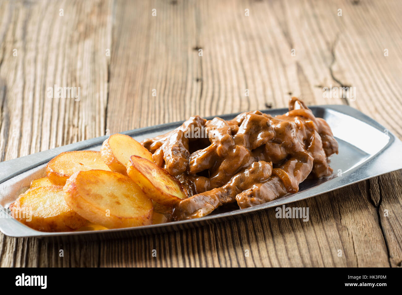 Bœuf Stroganoff, recette originale de plats russes. De fines lamelles de boeuf cuit dans la crème et la pâte de tomates, servi avec pommes de terre croquantes Banque D'Images