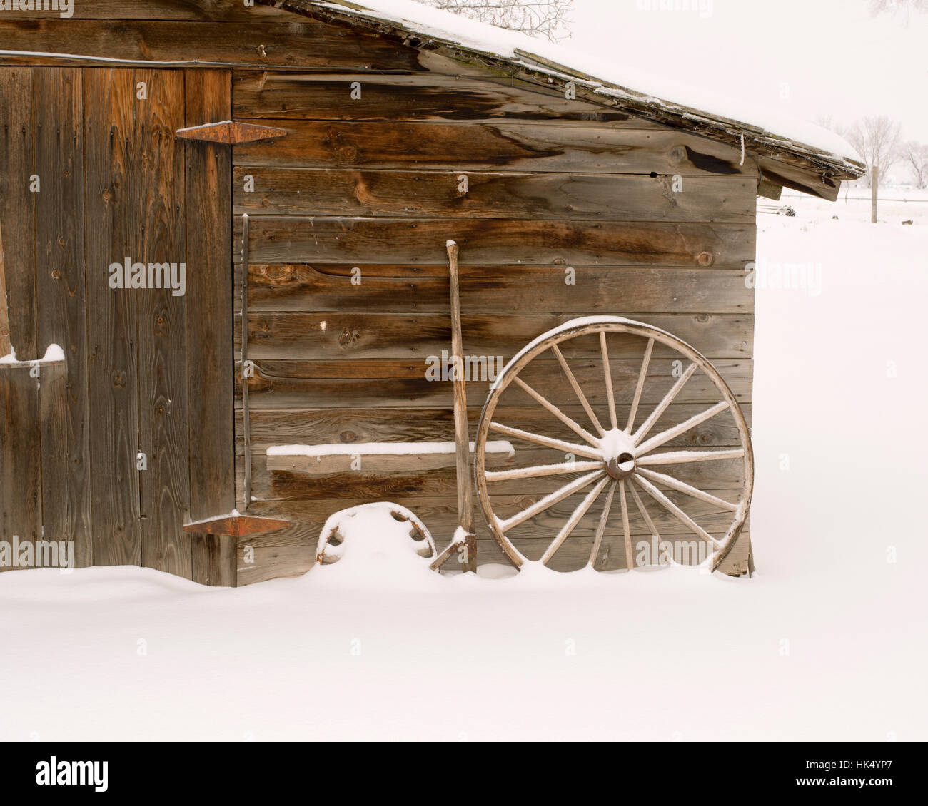 Hangar en bois patiné avec roues de charrette et la neige - square, neige légère Banque D'Images