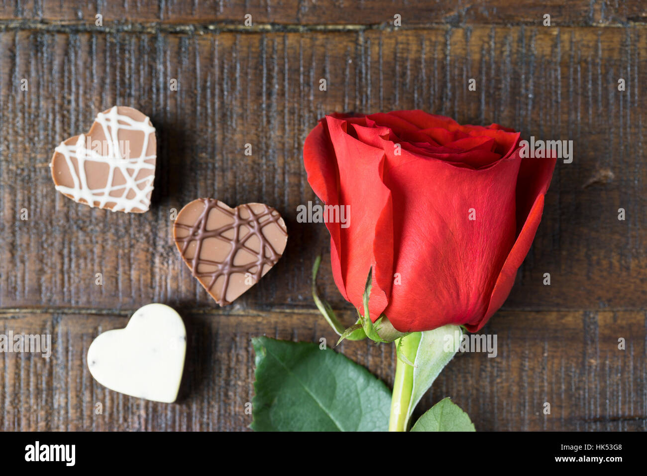 Rose rouge vif et trois chocolats en forme de coeur Banque D'Images