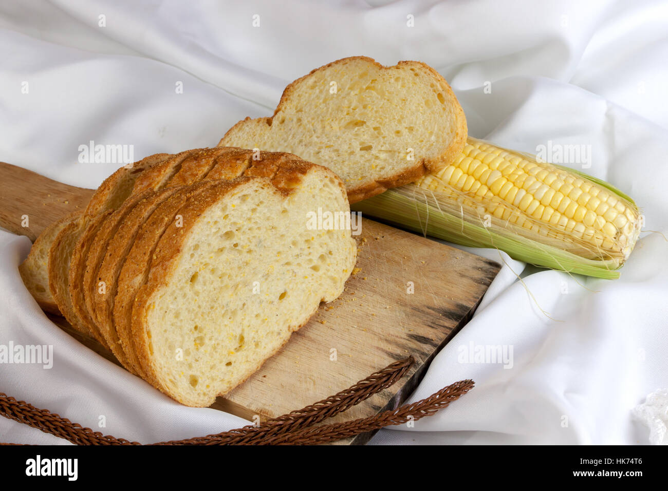 Pain de maïs sur le tissu blanc. Tranches de pain de maïs portant sur une planche à découper et les épis de maïs doux Banque D'Images