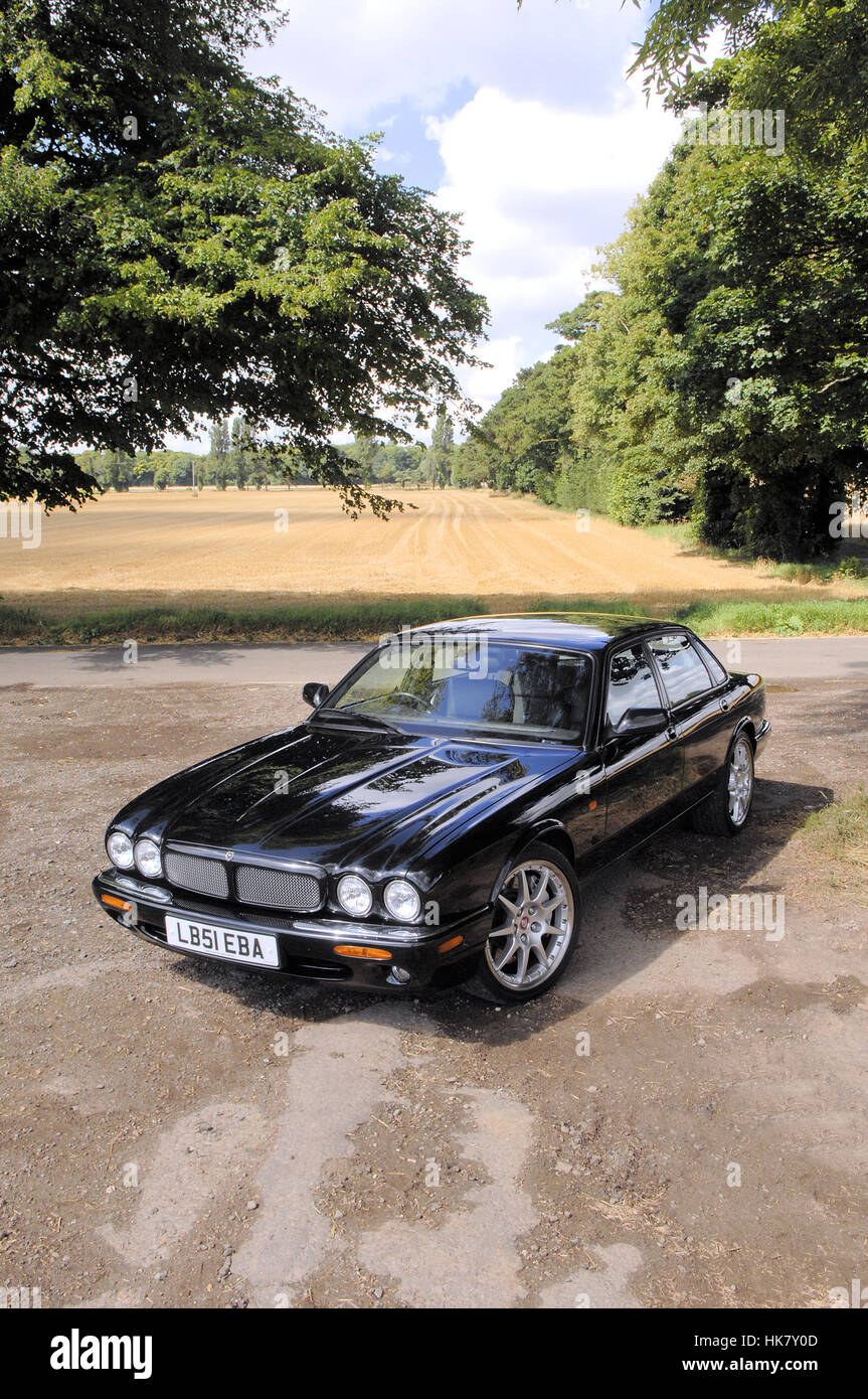 Jaguar XJR100 black voiture garée avec arbres Banque D'Images