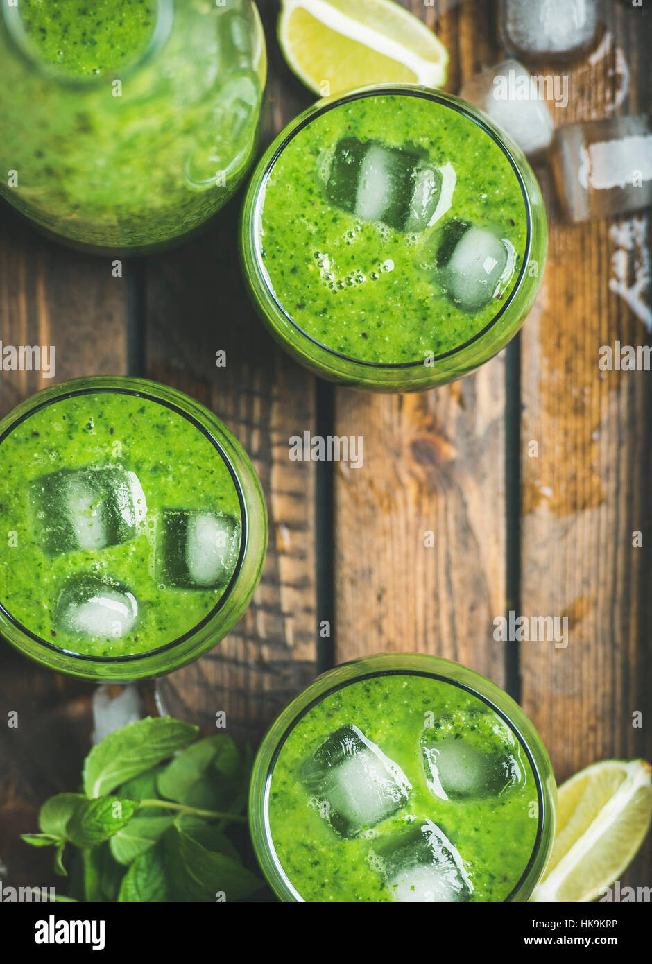 Smoothie vert frais en bouteille et des verres avec des cubes de glace, Menthe et citron vert plateau en bois, en vue d'en haut, selective focus, copiez l'espace. Manger propre, Detox, v Banque D'Images