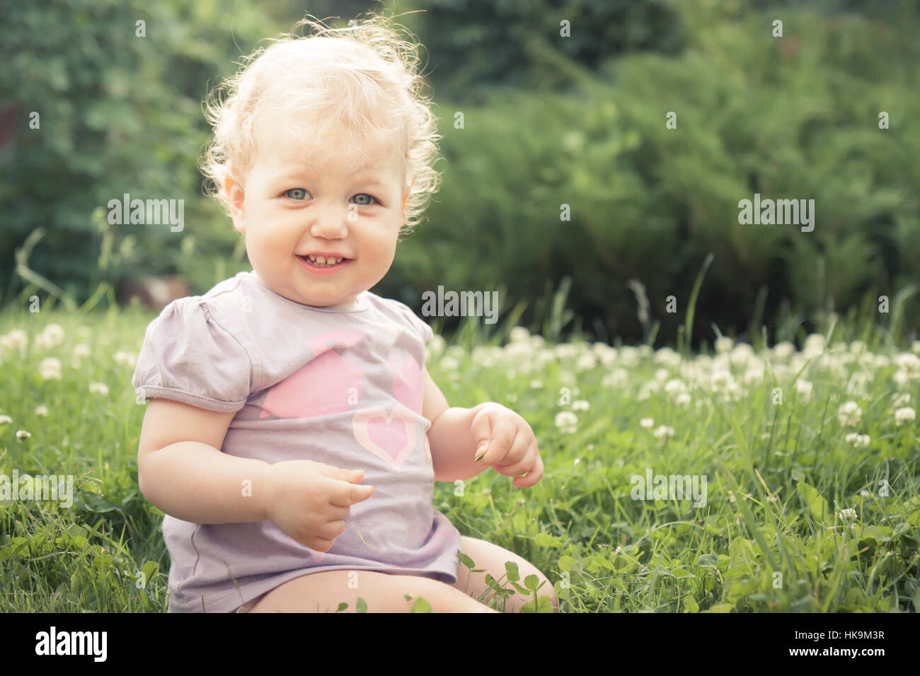 Petite fille timide sur l'herbe parmi les fleurs fleurissent en été Parc en journée ensoleillée avec copie espace Banque D'Images