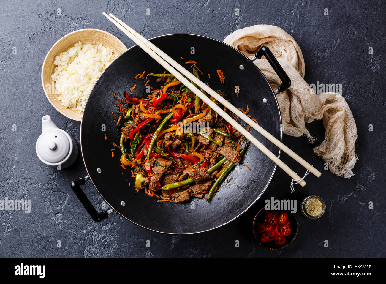 Faire revenir la viande de boeuf avec légumes et riz dans le wok casserole sur fond noir en sombre Banque D'Images
