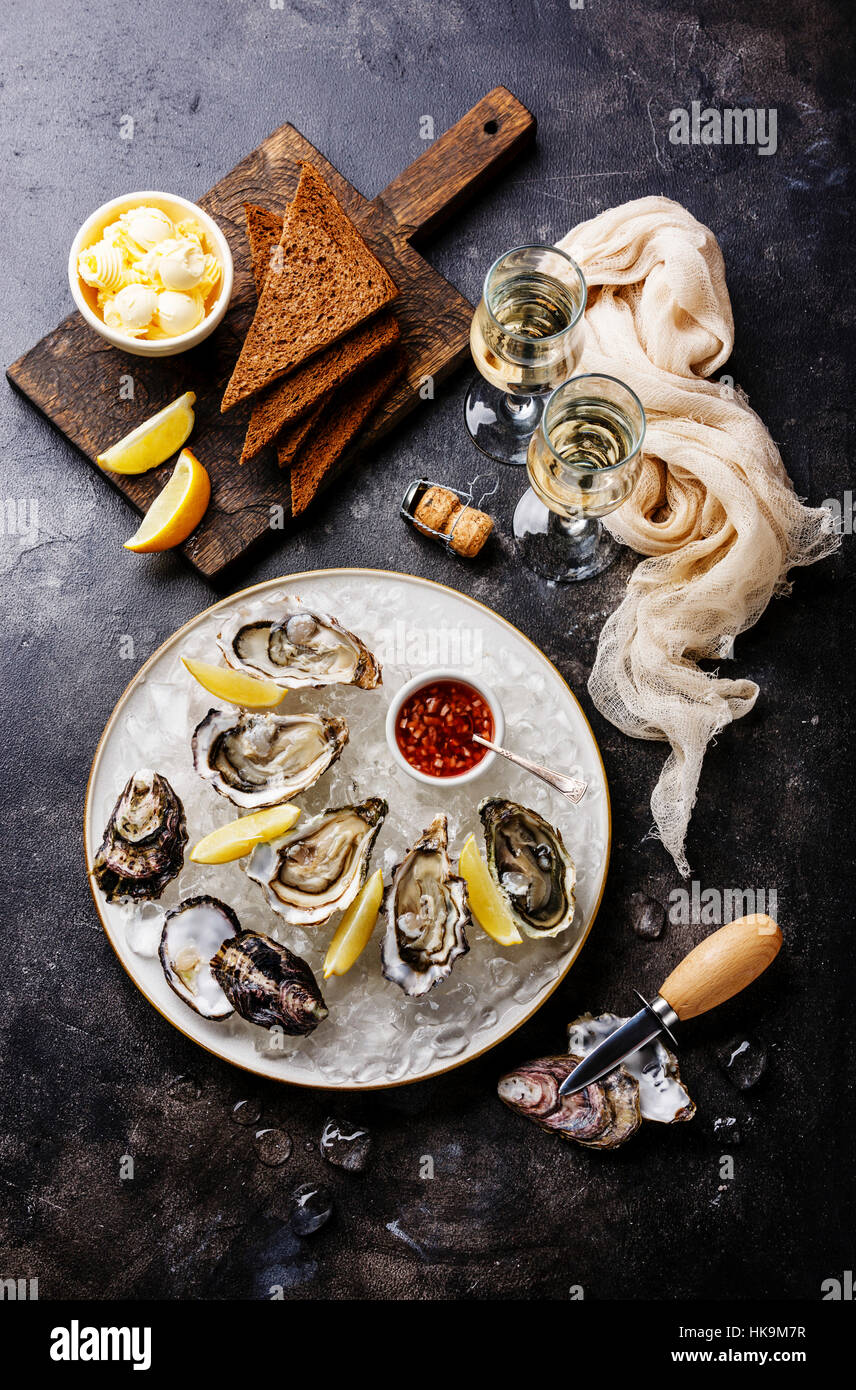 Ouvrir les huîtres avec du pain et du beurre et du champagne sur sombre texture background Banque D'Images Ouvrir les huîtres avec du pain et du beurre et du champagne sur sombre texture background Banque D'Images