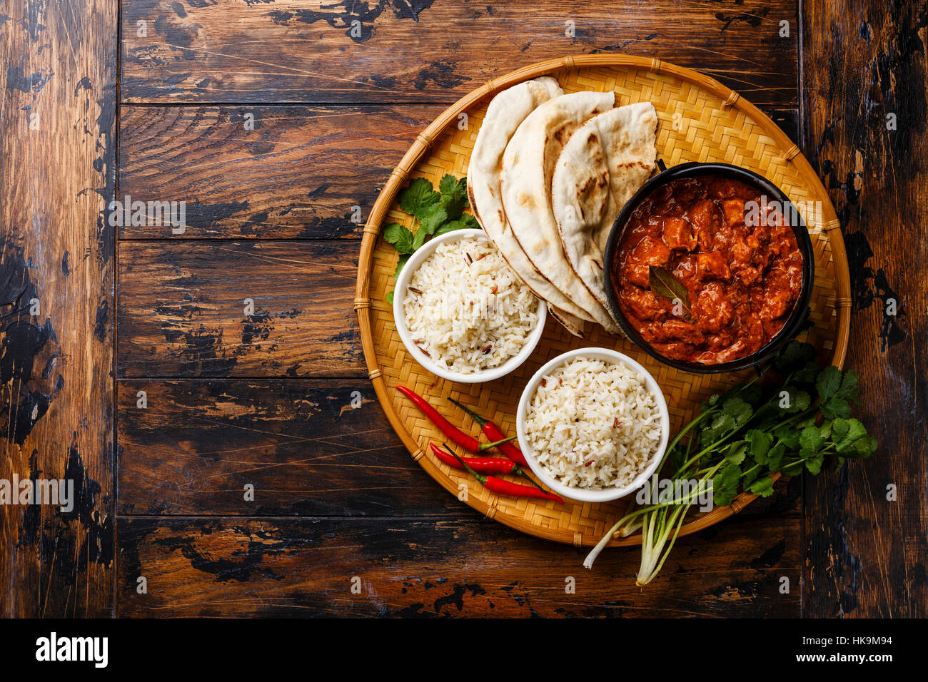 Poulet tikka masala curry épicé alimentaire de viande en pot en fonte avec du riz et du pain naan frais sur fond de bois copy space Banque D'Images