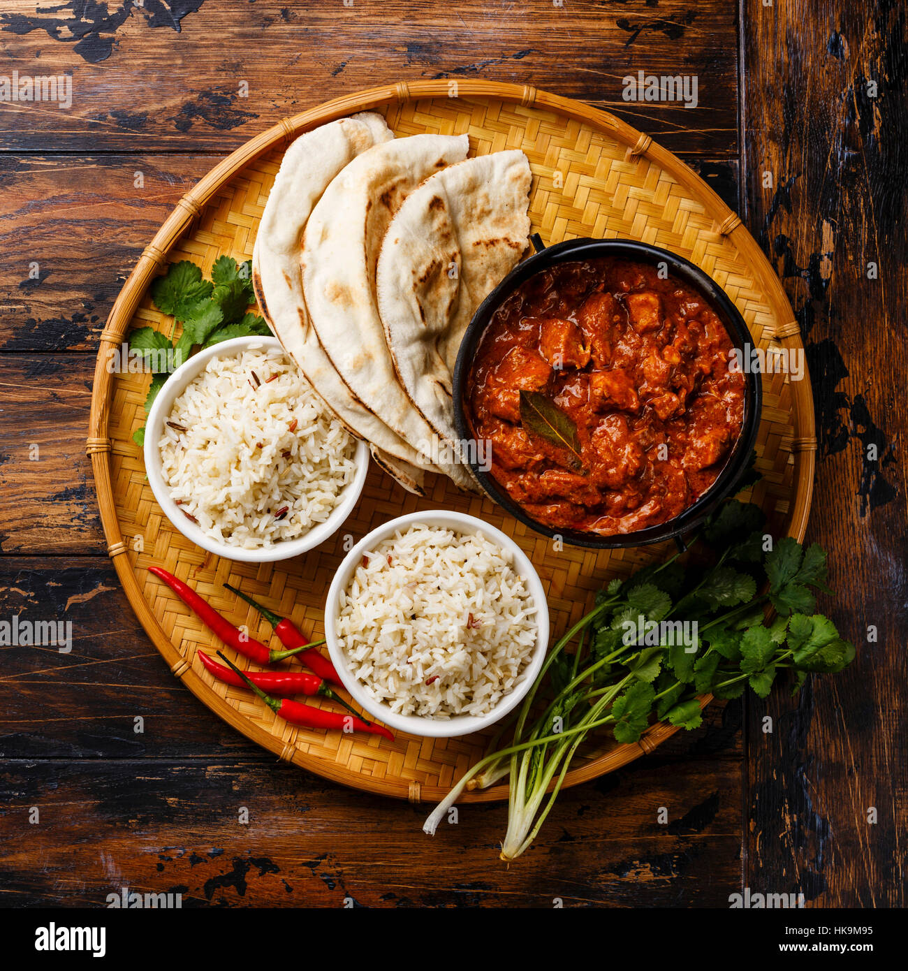 Poulet tikka masala curry épicé alimentaire de viande en pot en fonte avec du riz et du pain naan frais sur fond de bois Banque D'Images