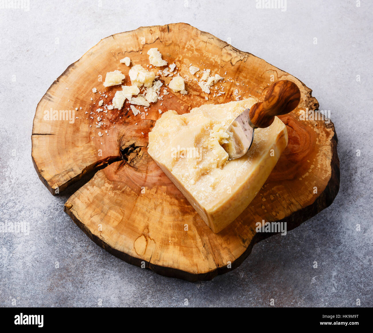 Fromage Parmesan sur planche de bois avec un couteau à fromage sur fond de béton gris Banque D'Images