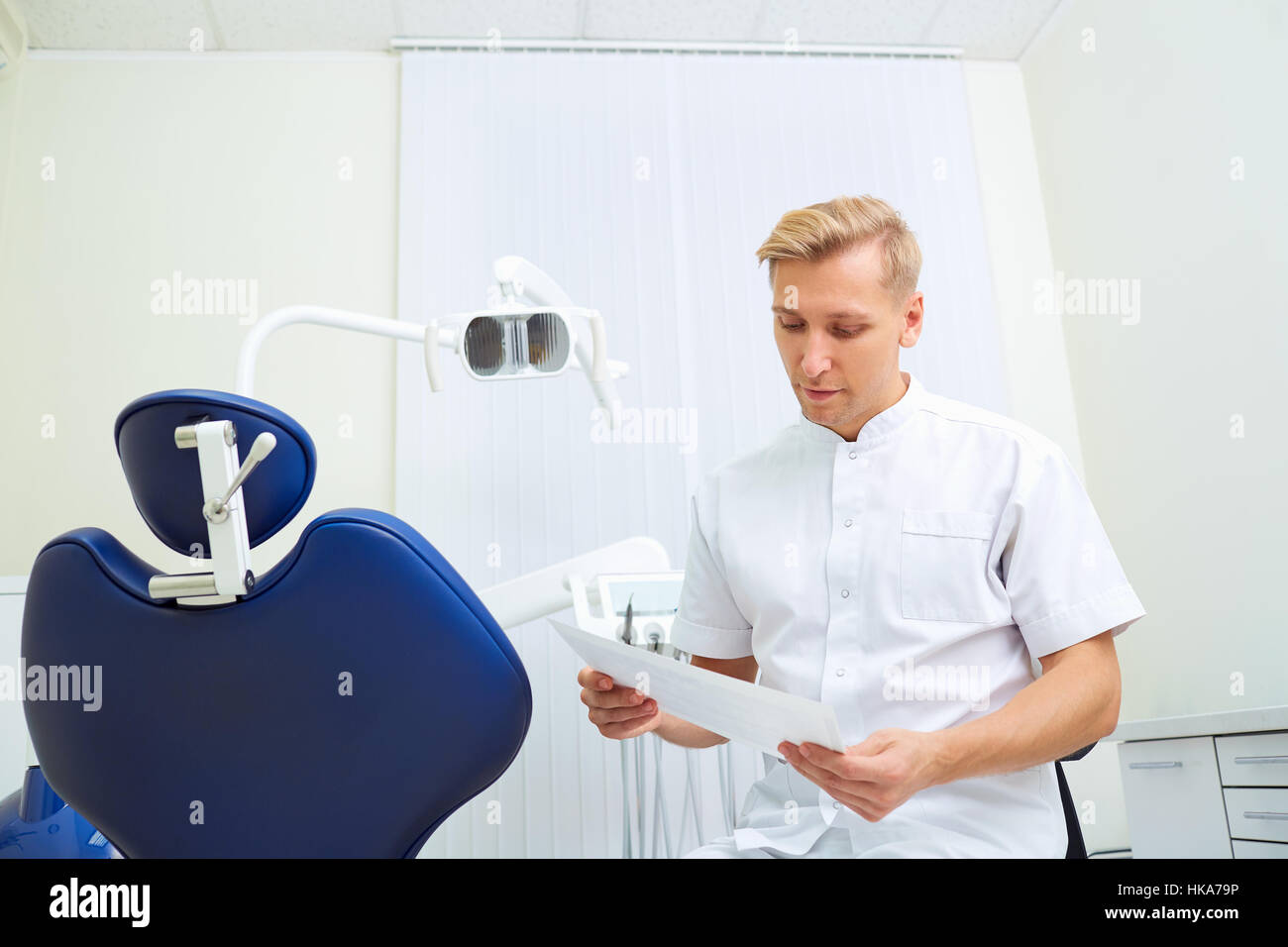 Dentiste homme blond la lecture d'un document dans le cabinet dentaire Banque D'Images