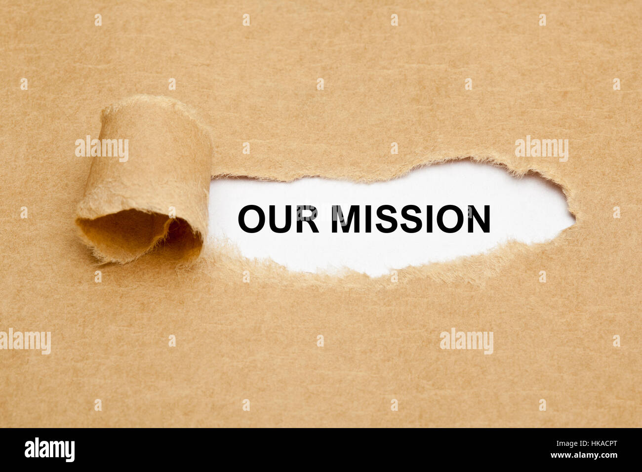 L'expression de notre Mission apparaître derrière déchiré papier brun. Banque D'Images