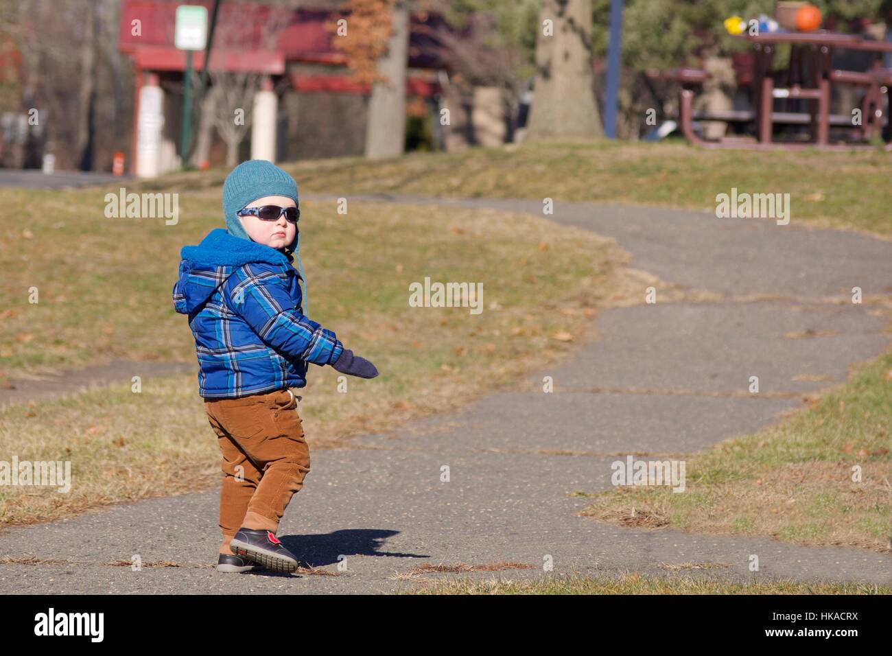Adorable bébé garçon descendre au chemin à l'extérieur du parc en hiver Banque D'Images